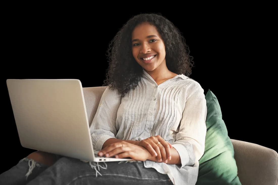 Mujer joven sonriente usando una computadora portátil en casa mientras navega por internet.